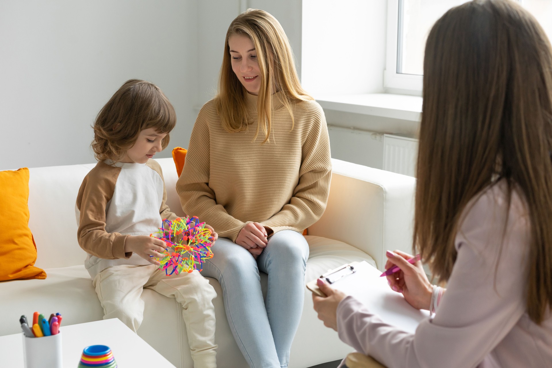 Happy mother with a little son at a reception with a child psychologist. School psychologist. Educational games. blurred foreground.